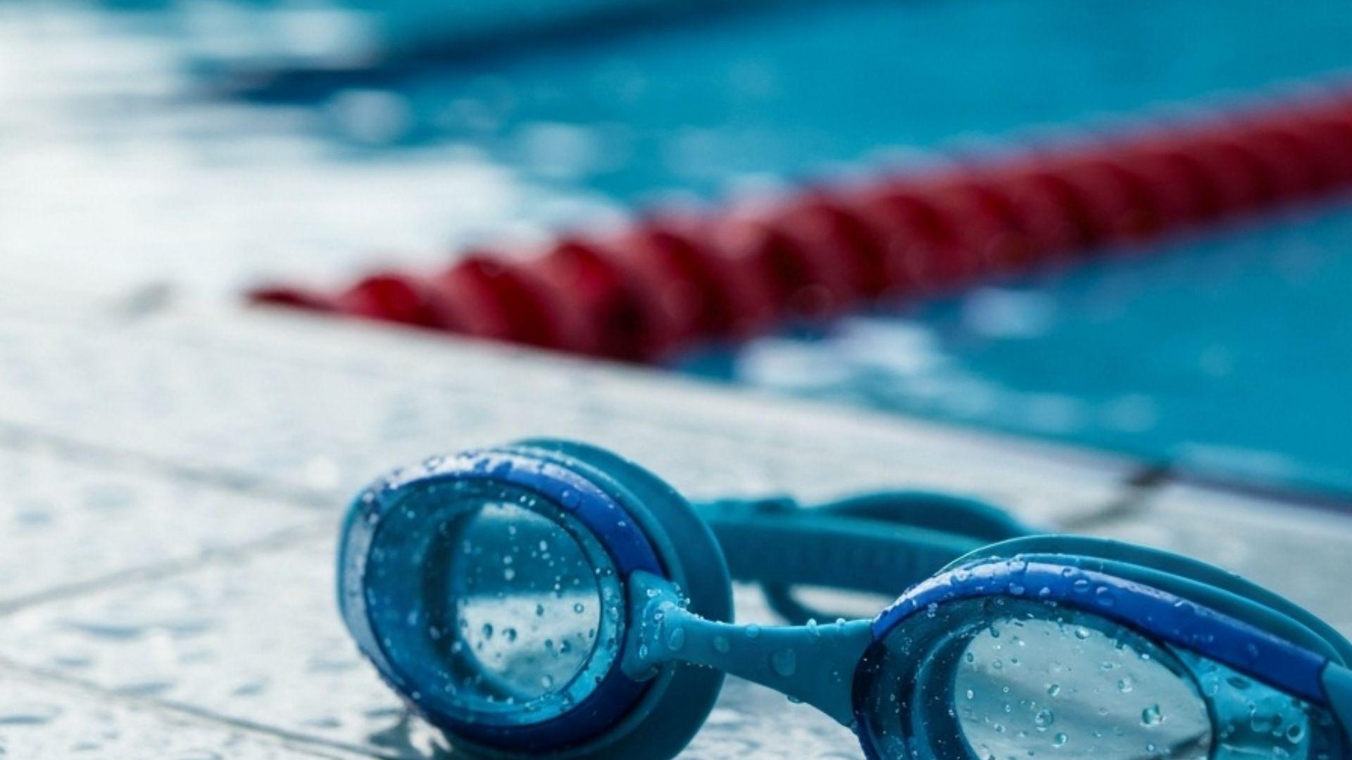Simglasögon på poolkant med vattendroppar
