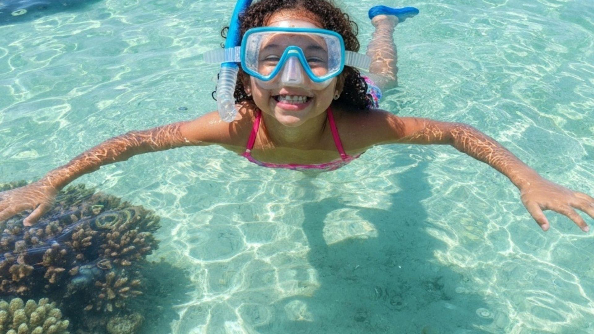 Barn med snorkelmask i klart vatten
