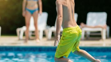 Pojke i badbyxor som hoppar i pool