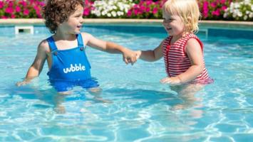 Barn med puddle jumper och simväst i pool