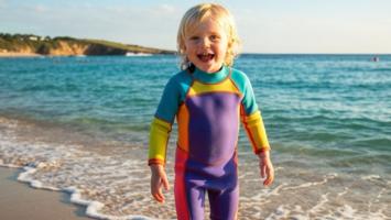 Barn i farverig våddragt på strand