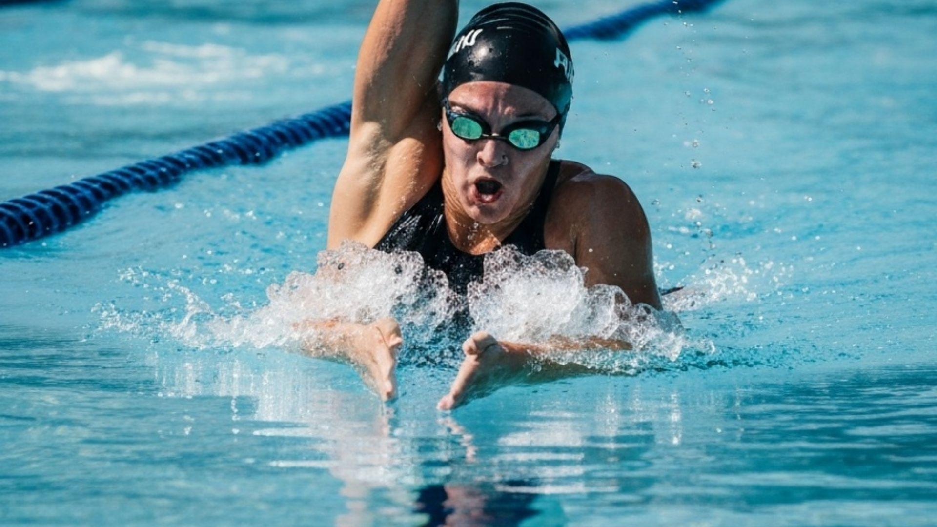 Simmare som utför bröstsim i pool