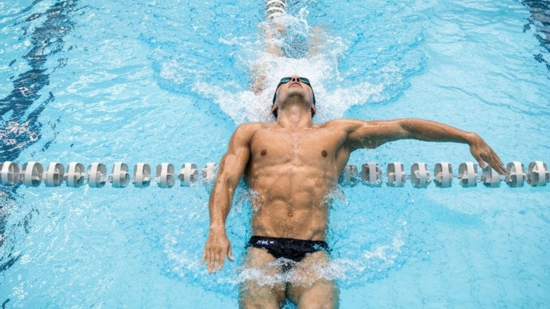 Simmare som utför ryggsim i poolbana